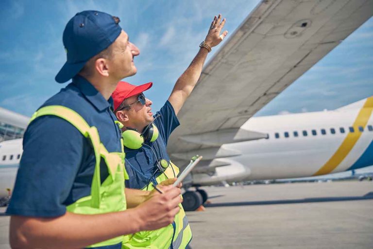 Aircraft Data Migration: Two technicians inspect an aircraft sitting on a tarmac.