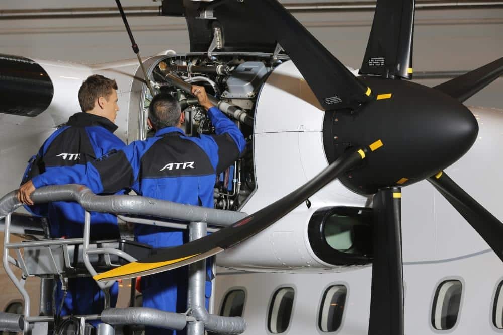 Two aircraft technicians inspecting a ATR engine in a hangar. 